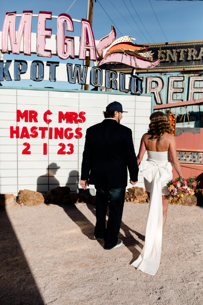 A bride with a short white wedding dress with a big bow on the back at the Neon Museum in Las Vegas