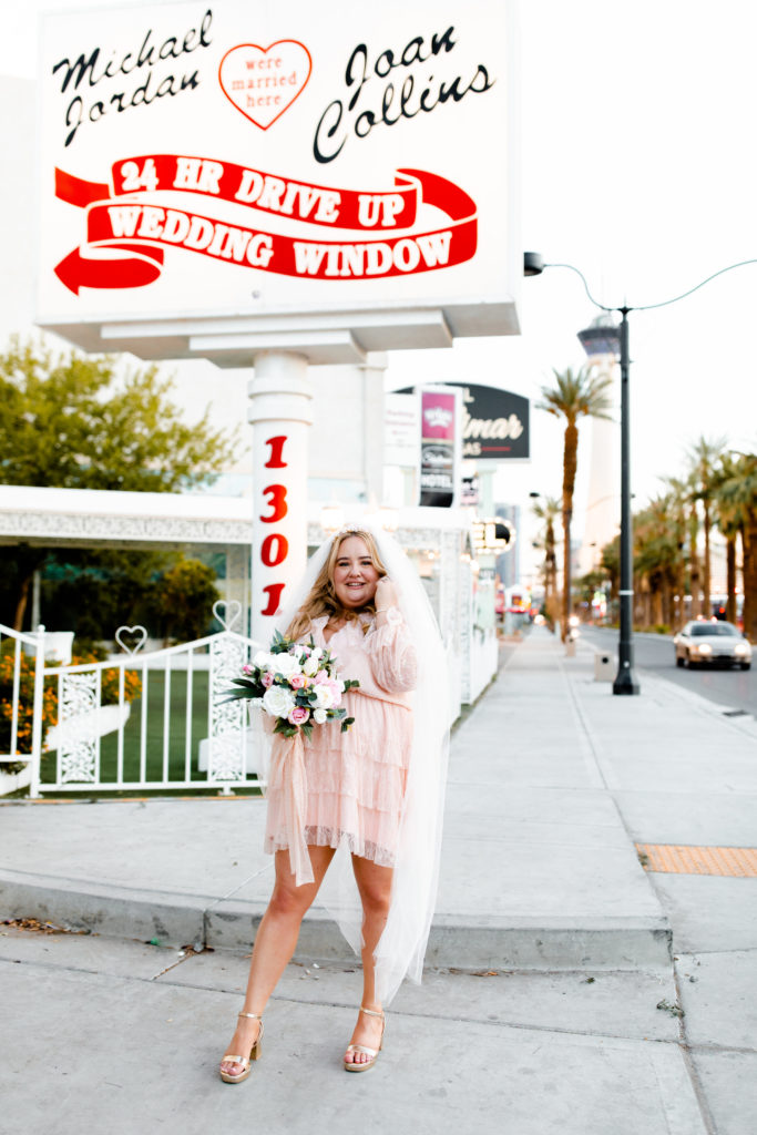 A bride in a short pink wedding dress with a long veil after her elopement at in Las Vegas