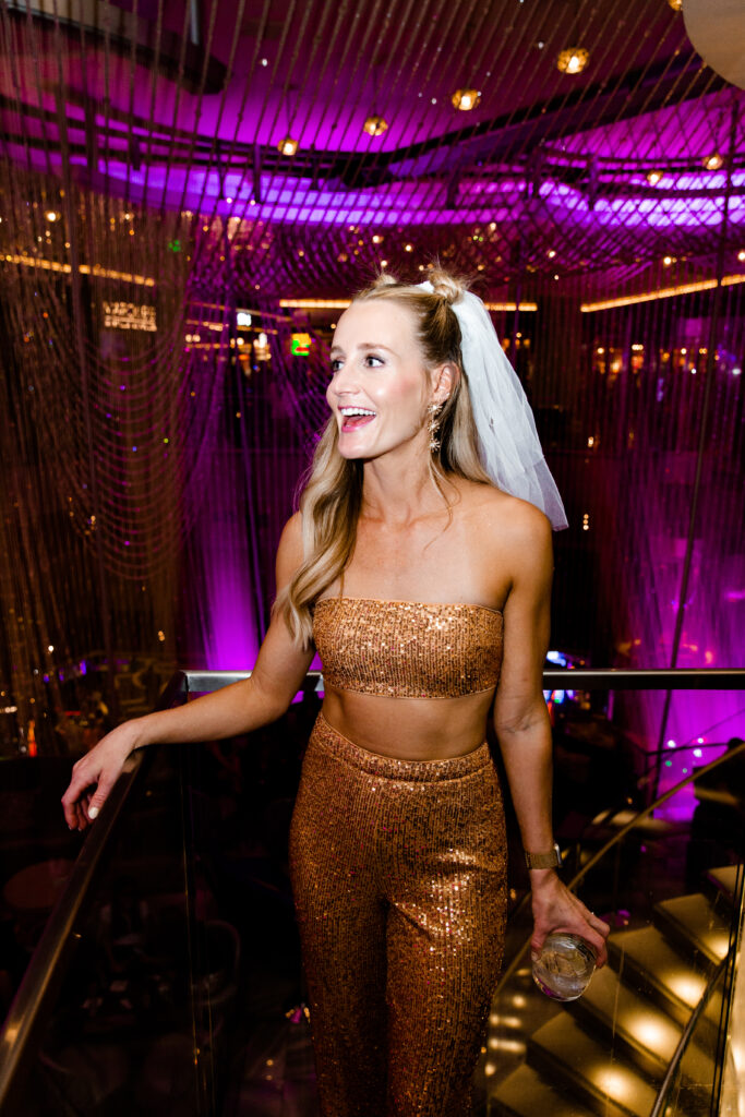 A bride at the chandelier bar wearing a rose gold two piece sequin set