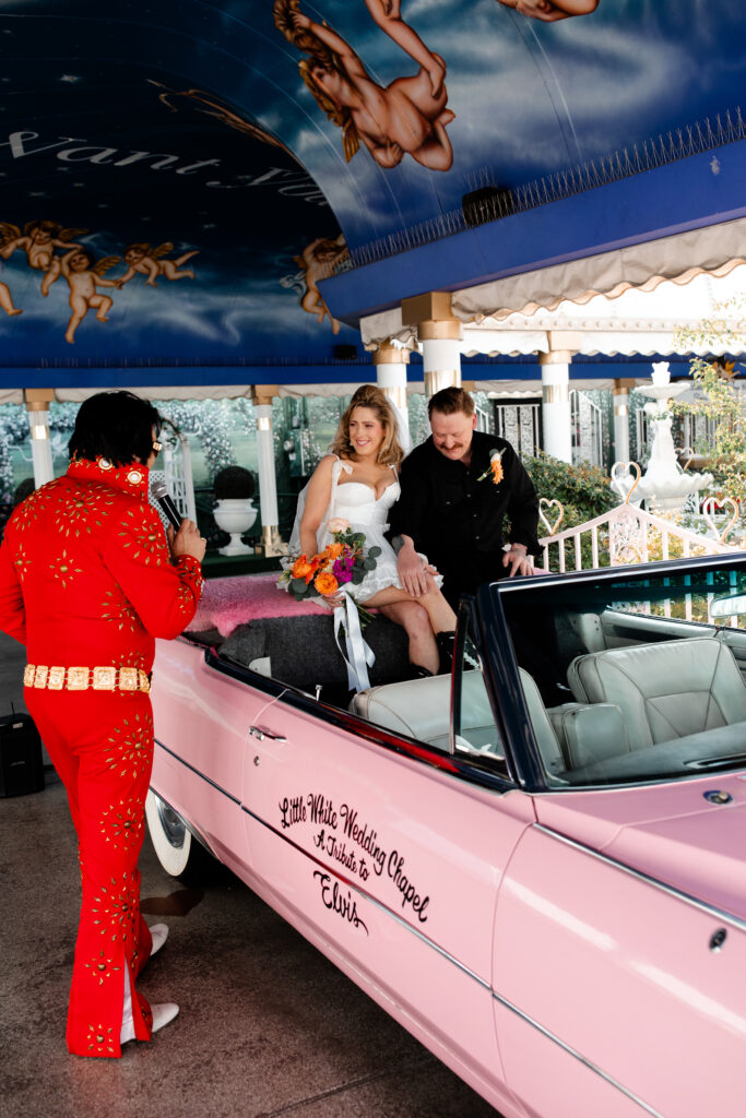 The newlyweds share a joyful moment in the backseat of the pink Cadillac at A Little White Chapel