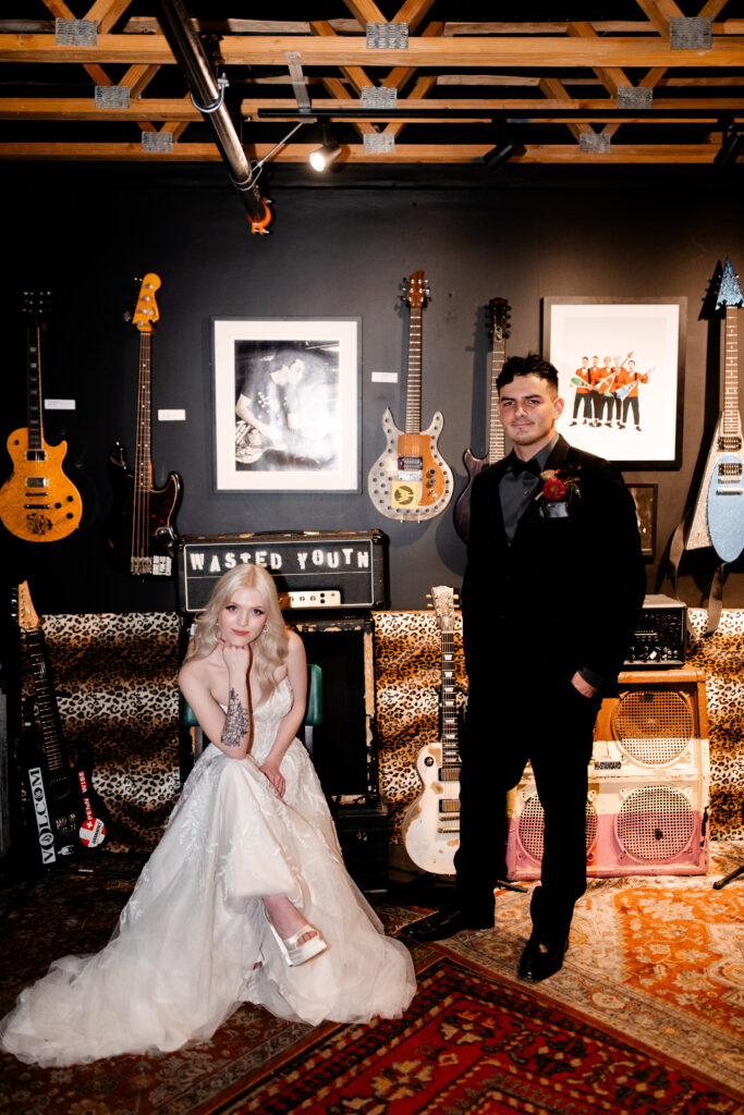 The bride and groom pose with electric guitars, adding a rock and roll flair to their wedding photos at the Punk Rock Museum.