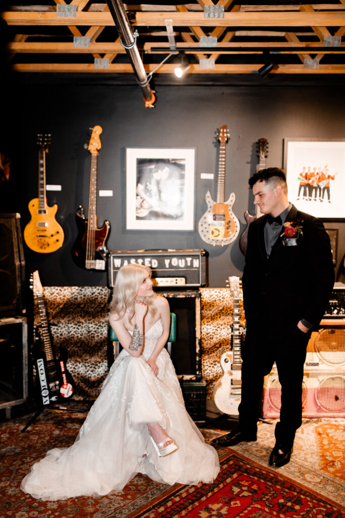 The bride and groom pose with electric guitars, adding a rock and roll flair to their wedding photos at the Punk Rock Museum.