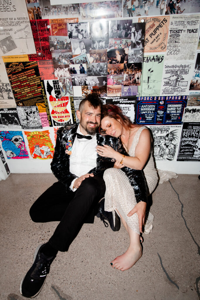 The bride and groom pose with iconic punk rock artifacts, blending their love for each other with their love for music.