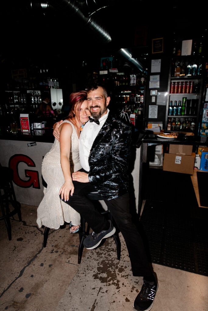 The bride and groom enjoy a celebratory moment at the museum's bar, raising their glasses in a toast with punk rock decor in the background.