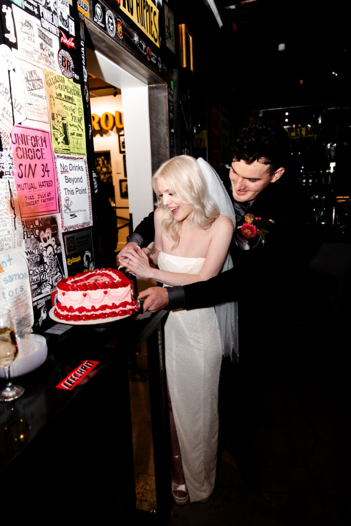 The bride and groom cut a red and pink traditional heart shaped wedding cake