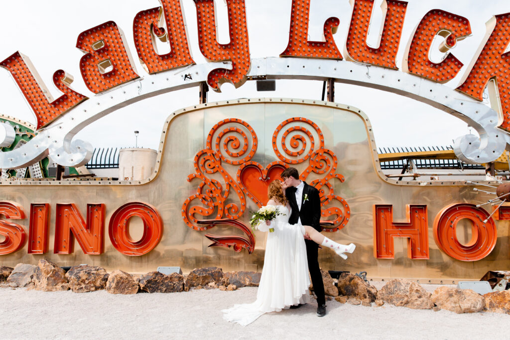 Las Vegas wedding photographer captures couple dancing in Neon Museum's neon art wearing tall white gogo boots