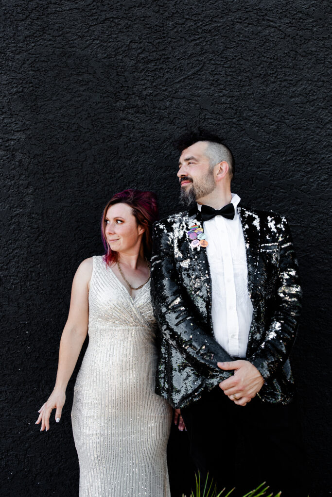 The bride and groom stand in front of the entrance to the Punk Rock Museum in Las Vegas, exuding excitement and punk rock style.