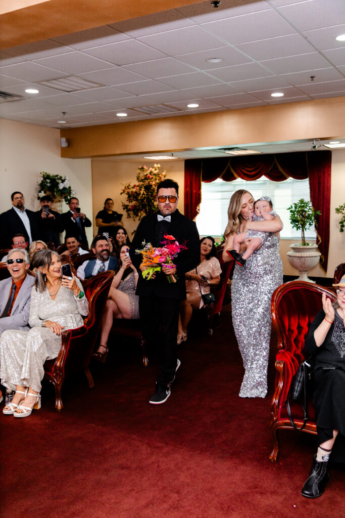 The bride and groom walk down the aisle together, smiling at their guests