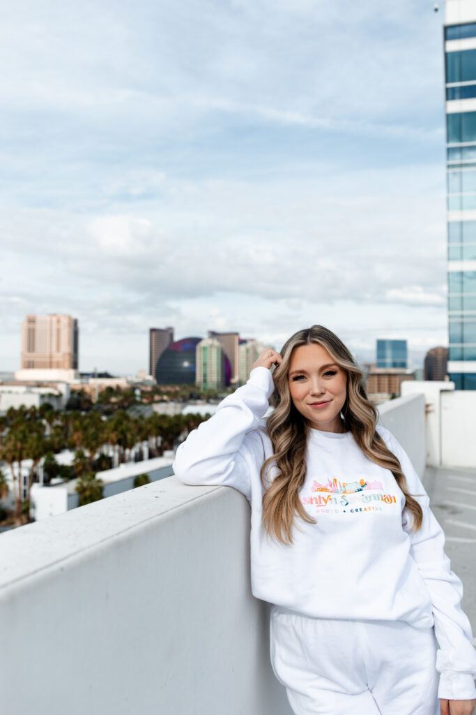 A Las Vegas wedding photographer stands confidently with the city's skyline behind, highlighting their professional brand and stylish approach.