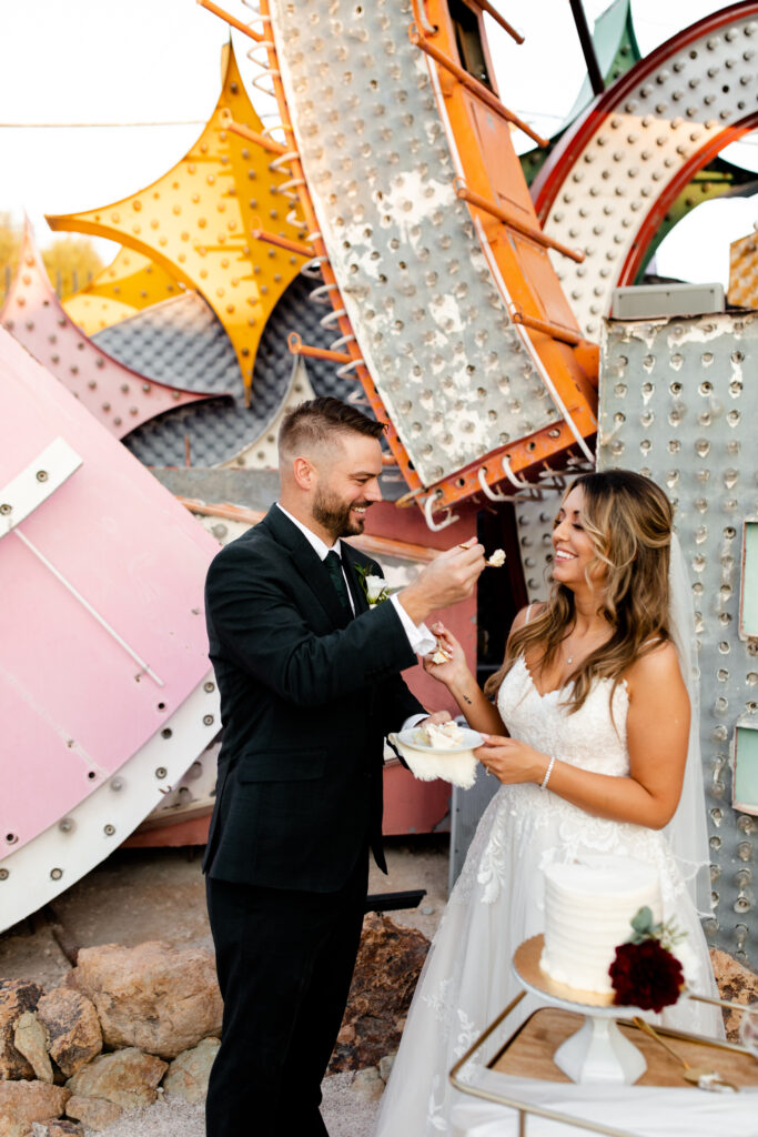 bride and groom cutting cake amidst neon art installations at Neon Museum