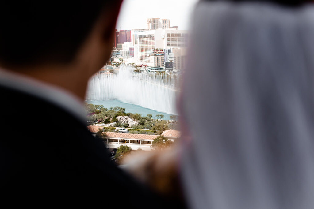 The bride and groom pose for a portrait on the balcony, with the luxurious backdrop of the Cosmopolitan suite and cityscape.