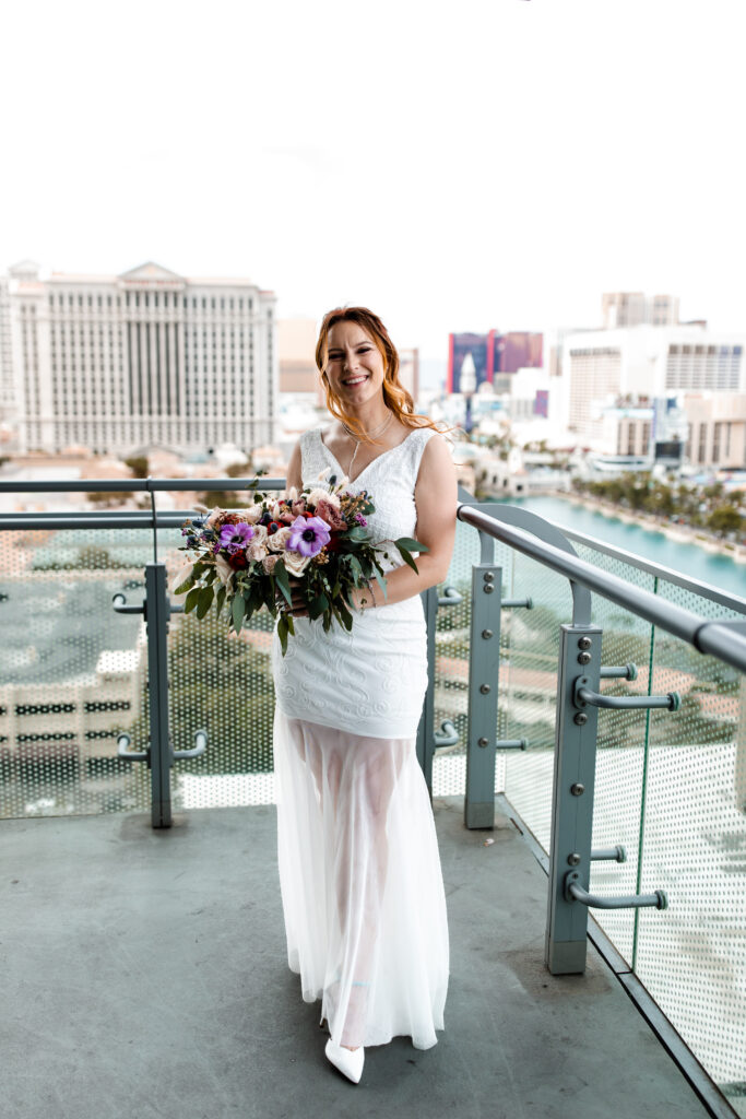 The bride poses gracefully on the balcony of the Cosmopolitan suite, with the Las Vegas skyline creating a stunning backdrop.