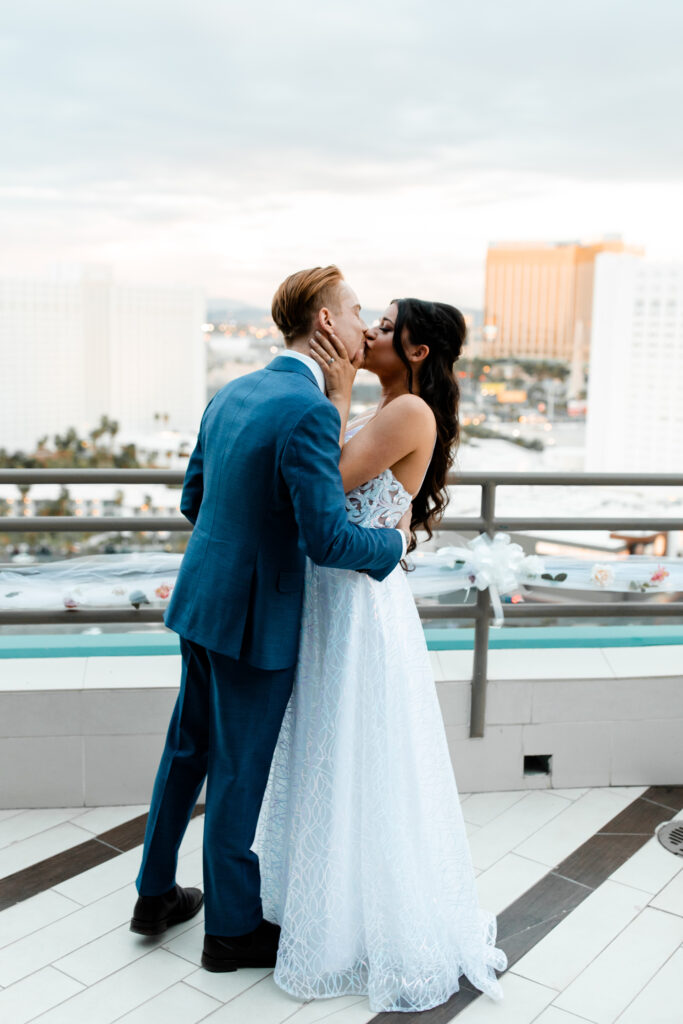 Las Vegas Photographer captures The newlyweds share a celebratory kiss on the terrace, framed by the glittering lights of the Las Vegas Strip.