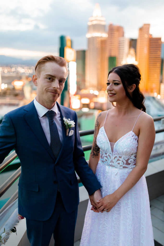 The bride and groom stand together on the terrace of their MGM Grand suite, overlooking the vibrant Las Vegas Strip.