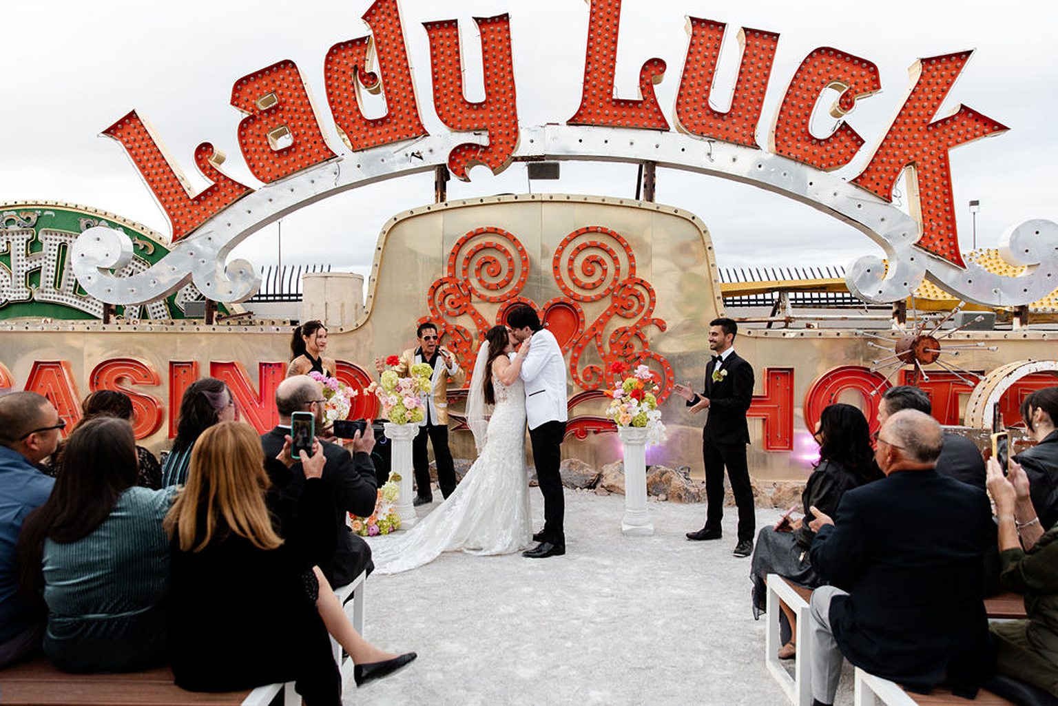 Bride and groom kissing during their Neon Museum wedding ceremony with  an Elvis officiant