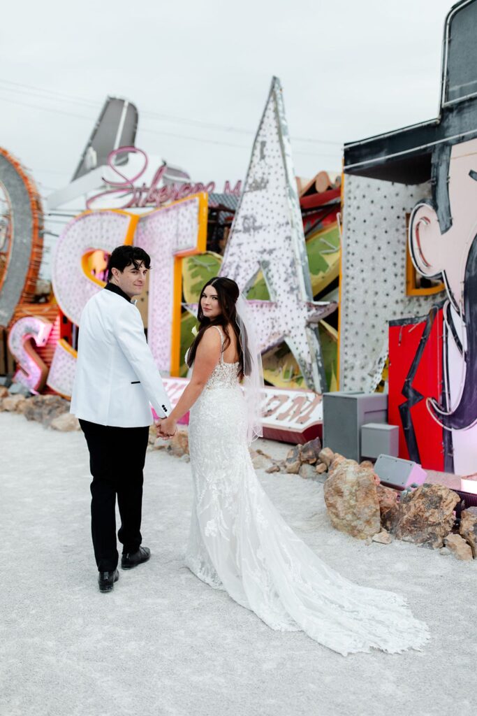 Bride and groom walking during their Bride and groom kissing during their Neon Museum wedding photos in Las Vegas