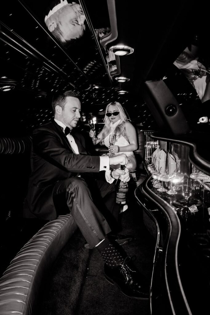 Black and white photo of a couple popping champagne in their limo for their engagement photos in Las Vegas