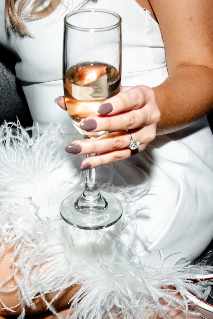 Woman holding a champagne glass and showing off her engagement ring