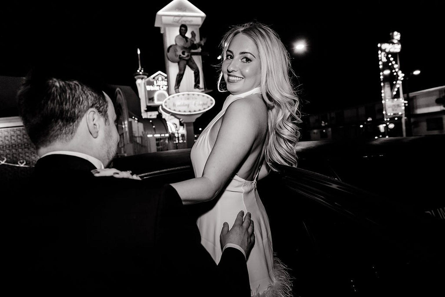 Black and white photo of a couple posing in front of The Little White Wedding Chapel for their engagement photos in Las Vegas