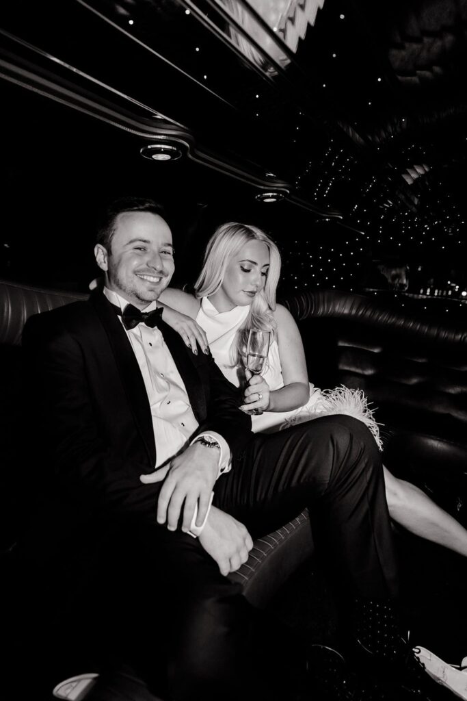 Black and white photo of a couple posing in their limo for their timeless engagement photos 