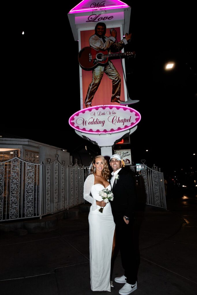 Bride and groom posing outside of The Little White Wedding Chapel for their Vegas night elopement photos.