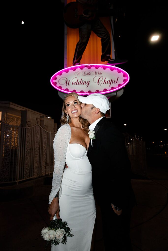 Groom kissing his bride on the cheek for their Vegas night elopement photos.