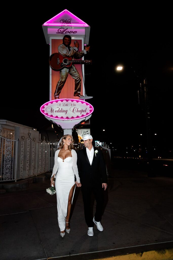 Couple walking down the sidewalk at night outside of The Little White Wedding Chapel in Las Vegas