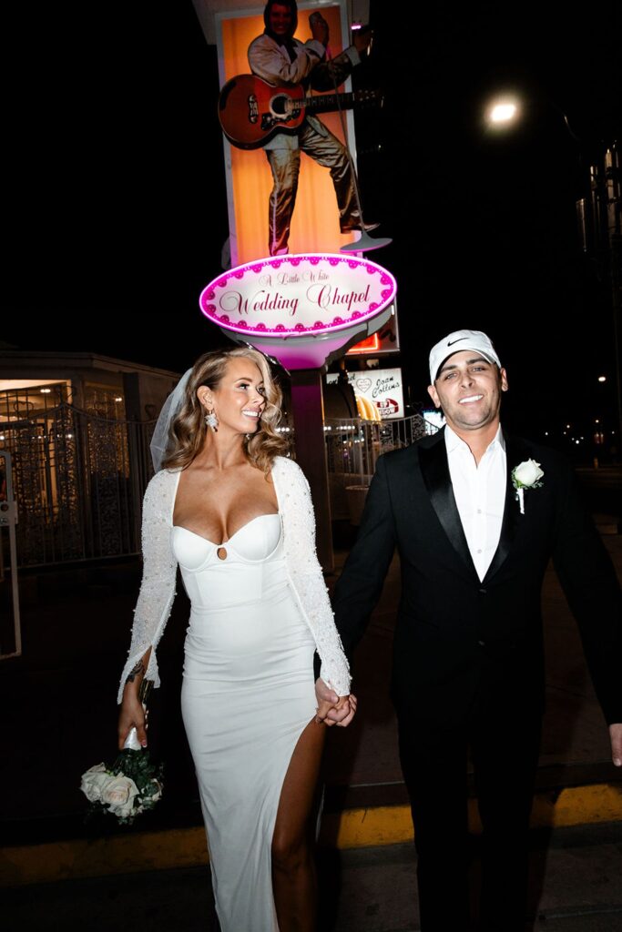 Flash elopement photos of a couple posing outside of The Little White Wedding Chapel in Las Vegas