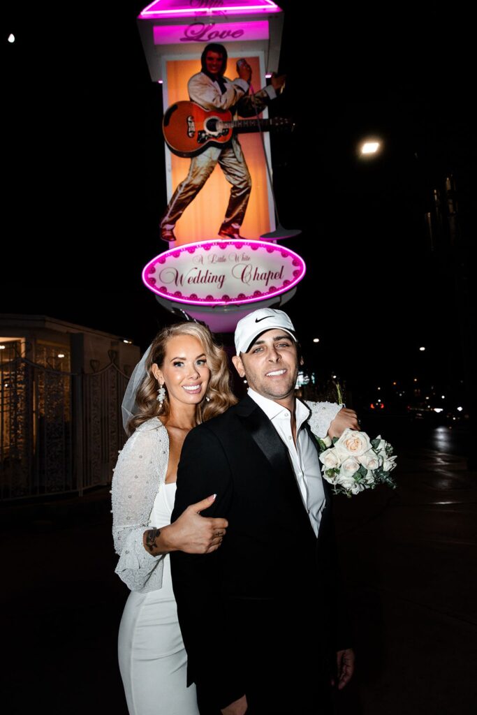 Bride and groom posing outside of The Little White Wedding Chapel for their night Vegas elopement photos.