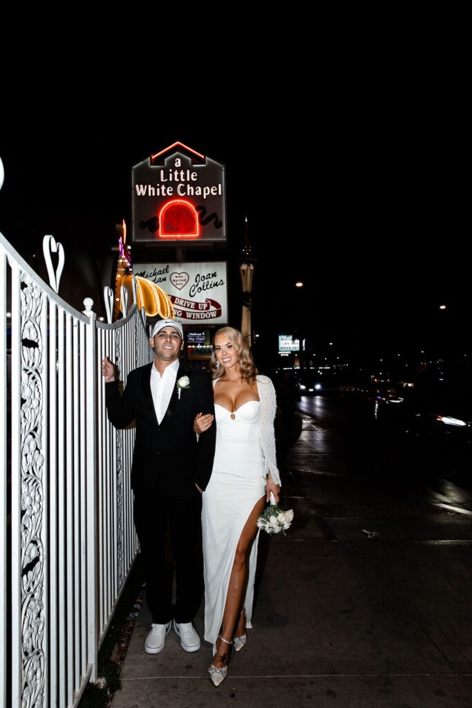 Bride and groom posing next to the white gate at The Little White Wedding Chapel Las Vegas