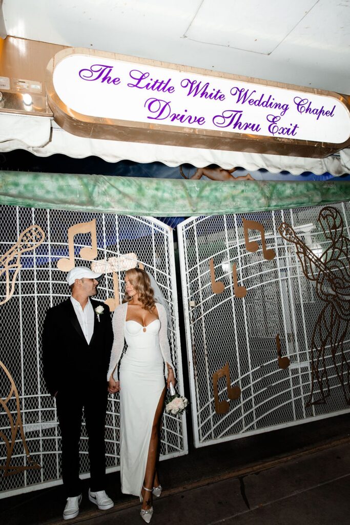 Bride and groom posing outside of The Little White Wedding Chapel Drive-Thru Exit