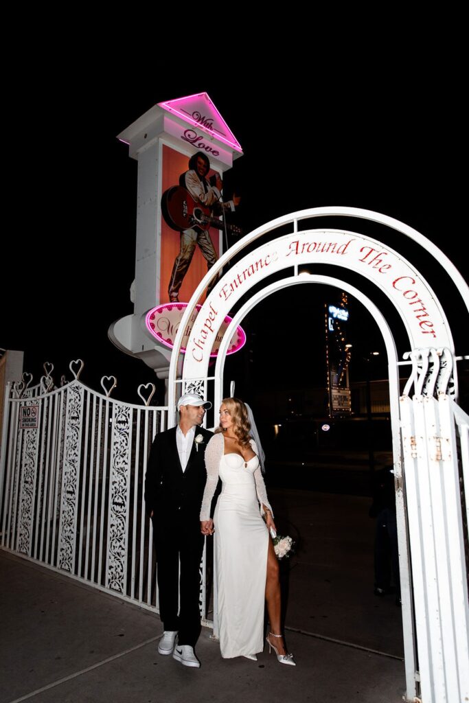 Bride and groom posing against a white gate outside of the LWC