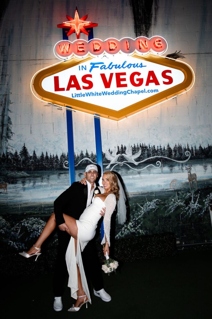 Bride and groom posing with the fabulous Las Vegas sign at The Little White Wedding Chapel Las Vegas NV