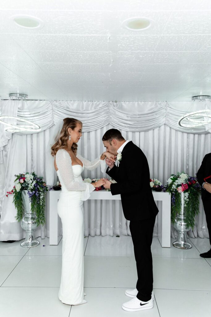 Groom kissing his brides hands during their ceremony