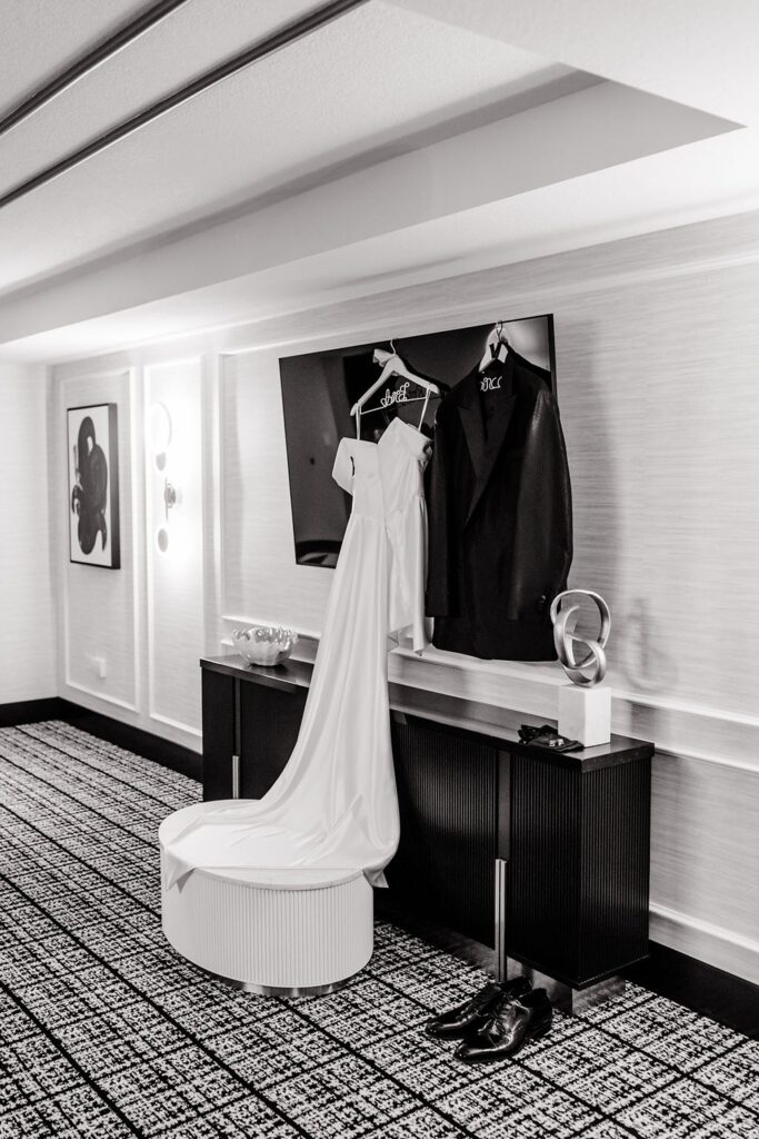 Black and white wedding detail shot of the brides dress and grooms suit hanging