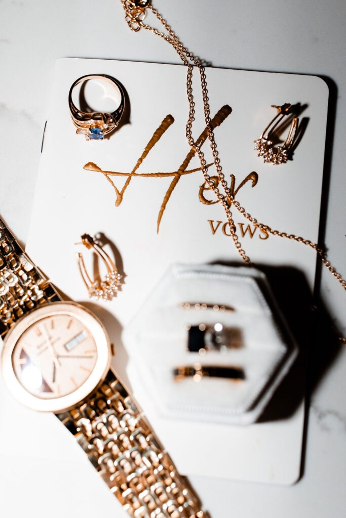 Jewelry, watch, and her vow book wedding detail shot
