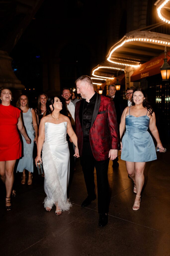 Bride, groom. and their wedding party taking portraits downtown
