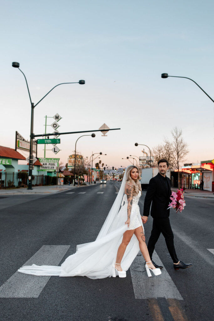 Couple holding hands and walking across the street for their downtown vintage Las Vegas wedding photos