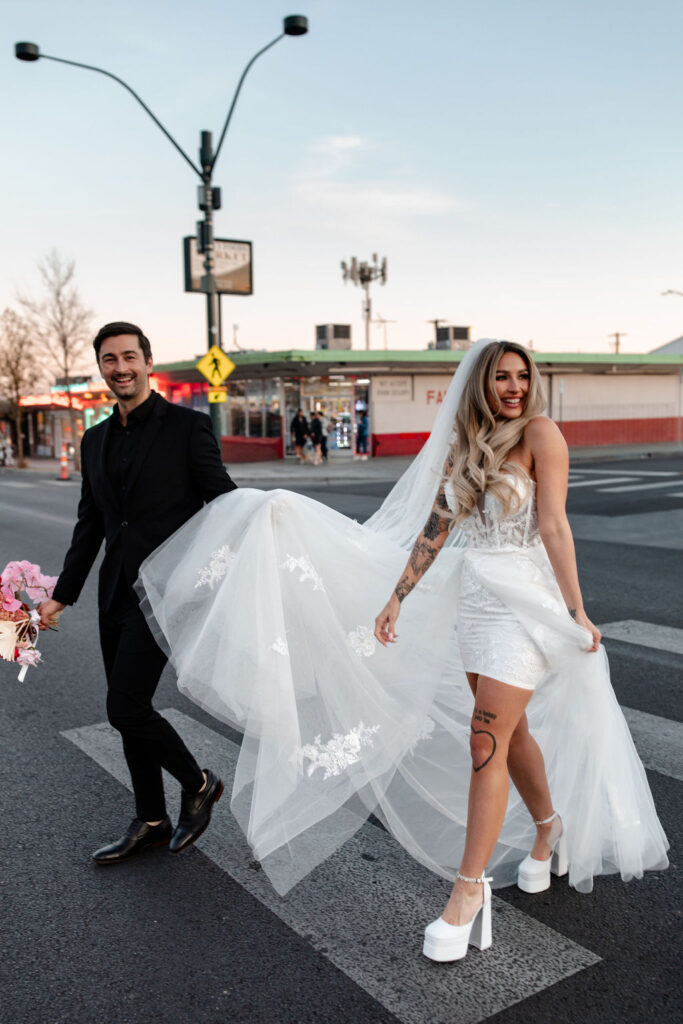 Couple holding hands and walking across the street for their downtown vintage Las Vegas wedding photos