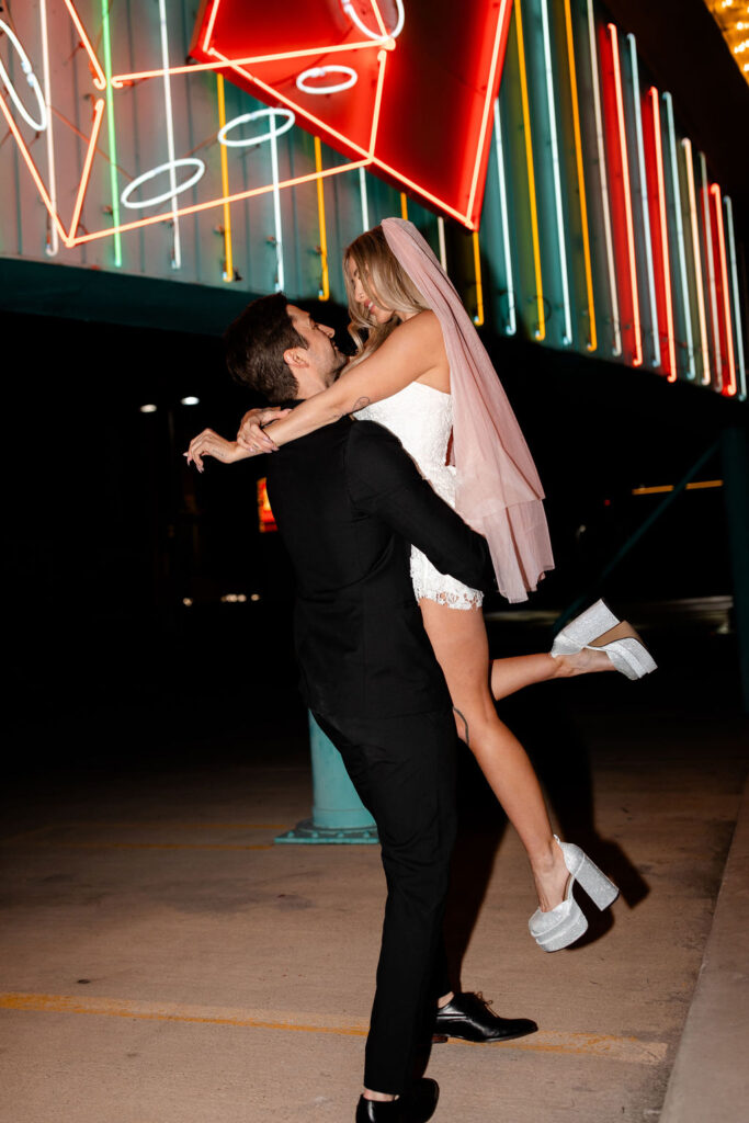 Man picking up his bride during their vintage Las Vegas wedding photos on Binion's Rooftop
