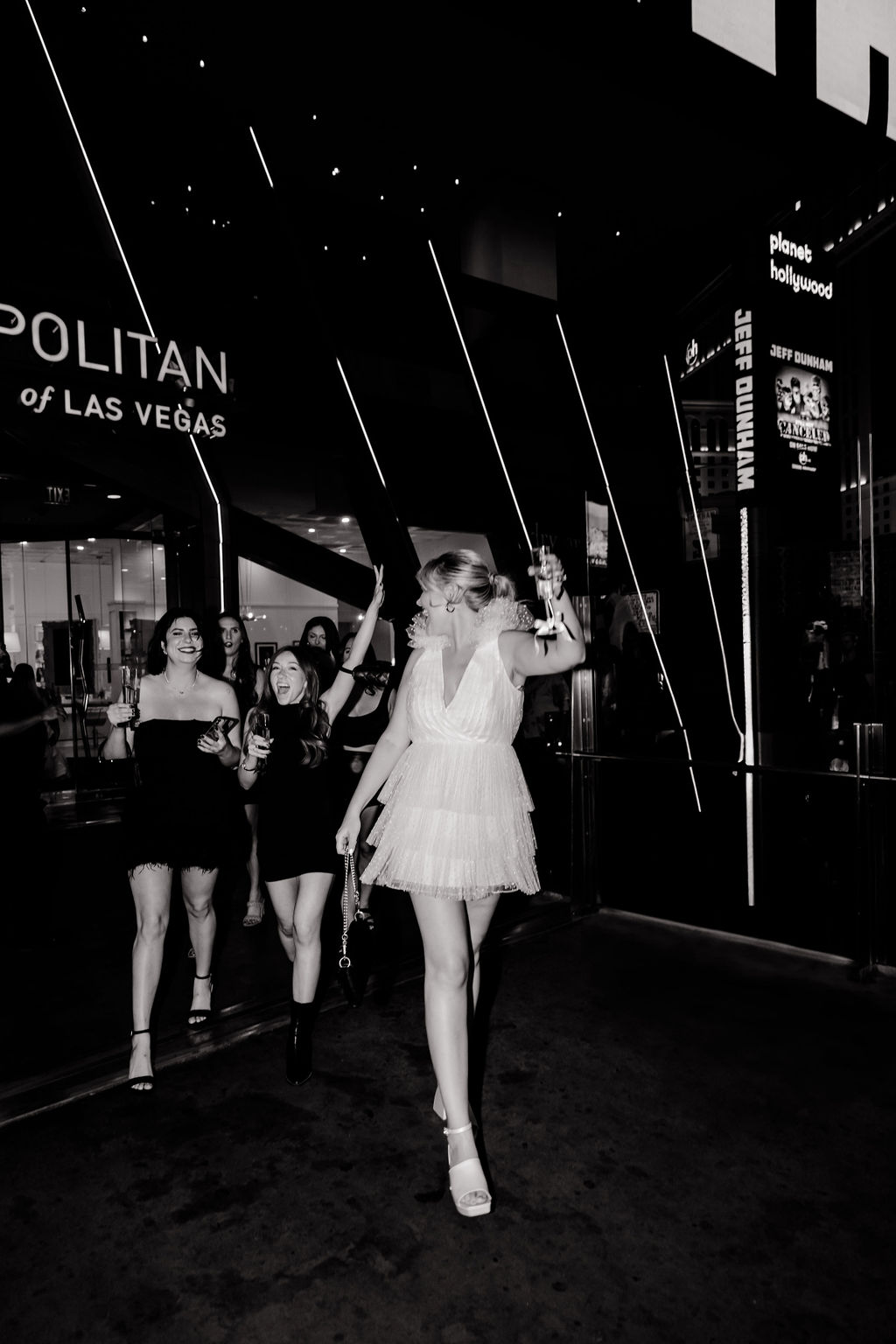 Black and white photo of a bride and her friends walking out of The Cosmopolitan in Las Vegas
