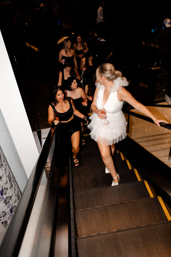 Bride and her friends riding up an escalator