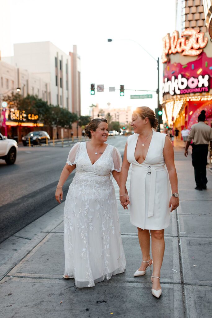 Couple holding hands and walking on Fremont Street for their downtown Las Vegas wedding photos at sunset
