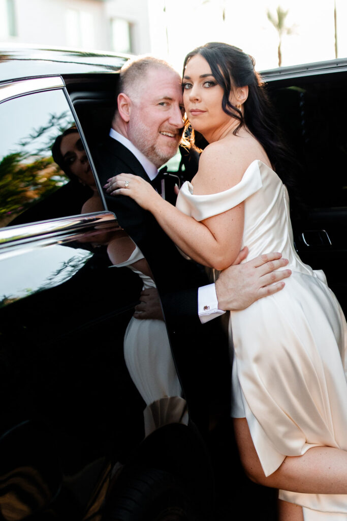 Bride and groom posing for their Las Vegas wedding photos with a limo