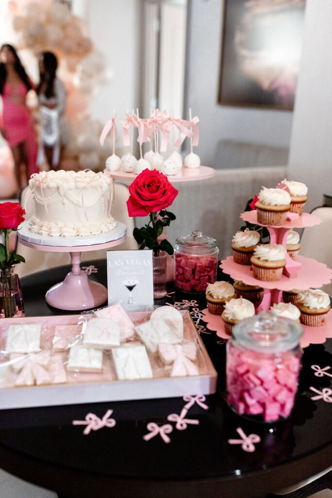 Full dessert table with themed treats and pink decor for a Las Vegas bachelorette celebration