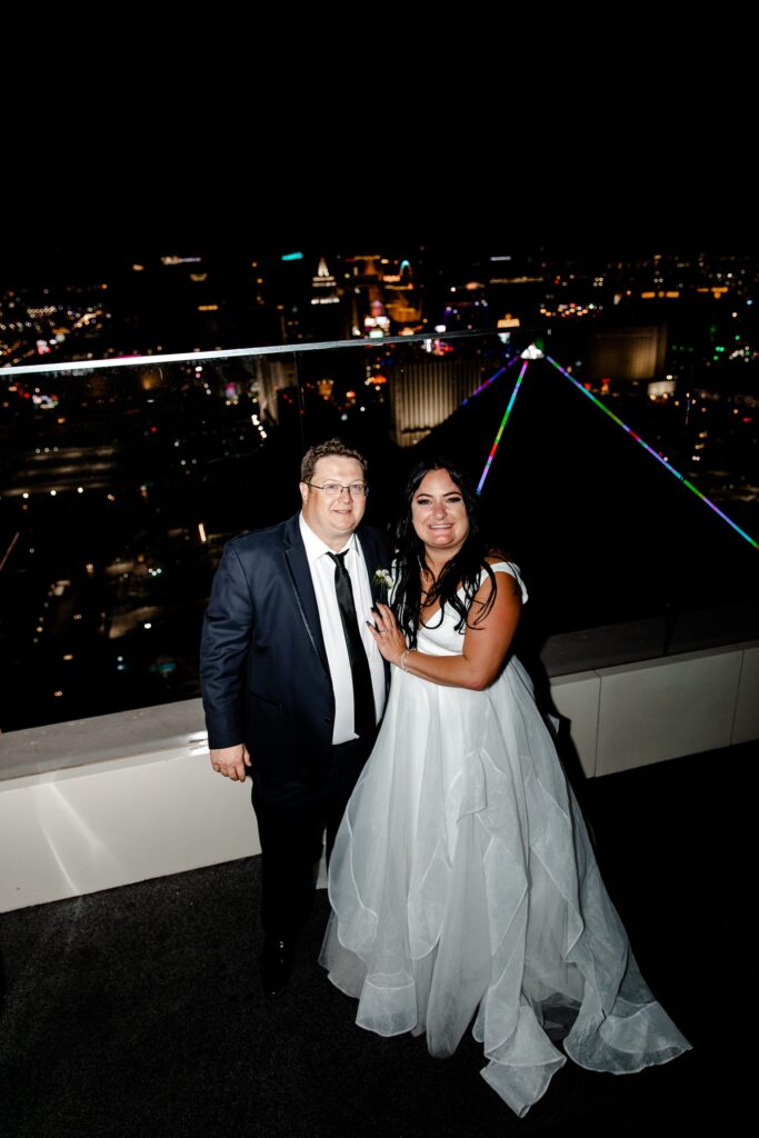 Bride and groom posing on the balcony of Skyfall Lounge at The W