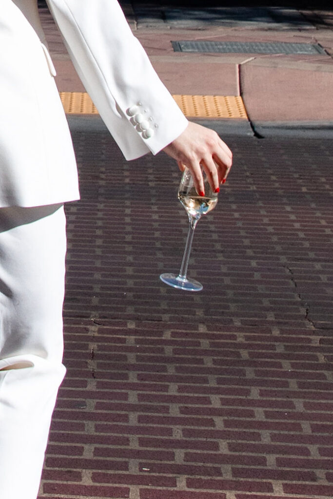 Bride holding a glass of champagne as she walks across the street