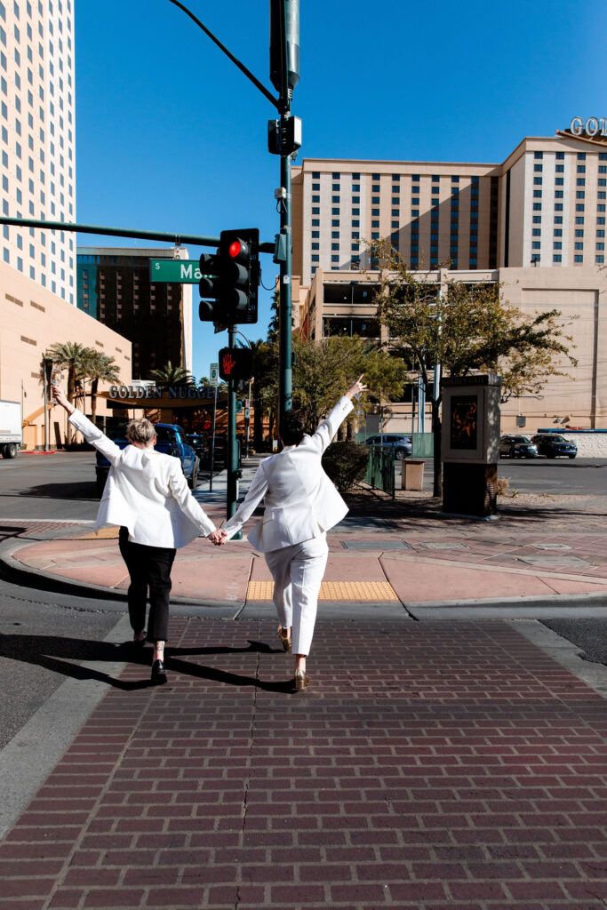 LGBTQ+ couple walking across the street for her downtown Las Vegas wedding photos