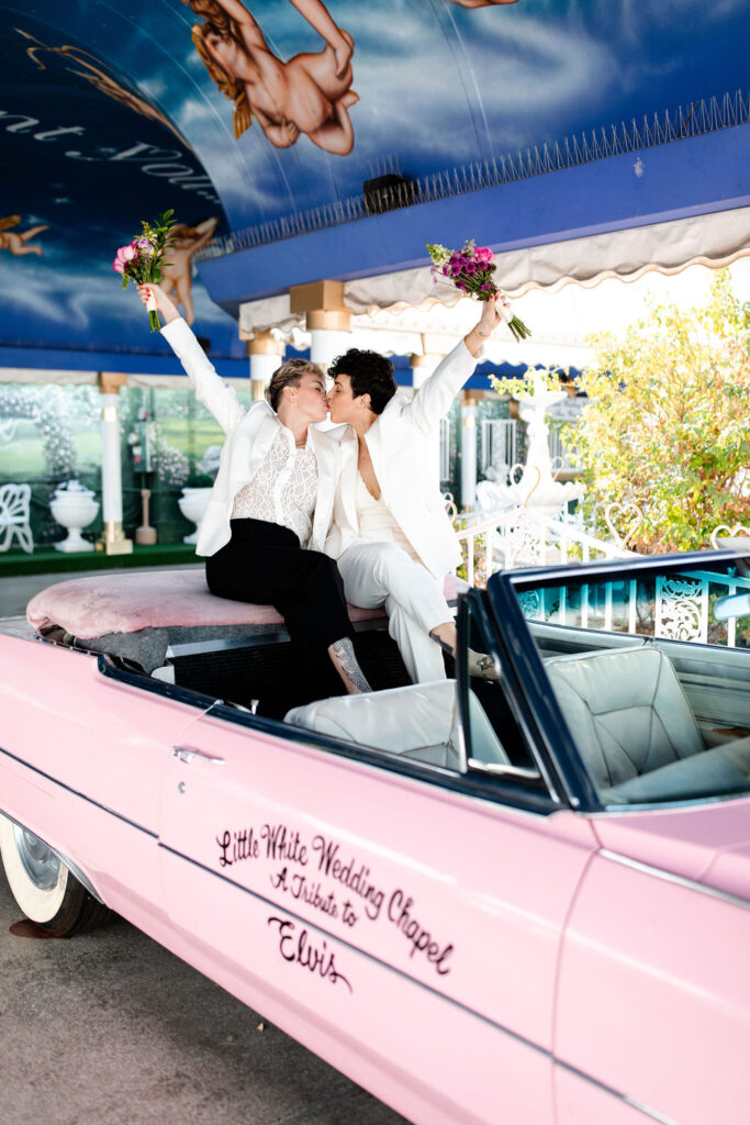 LGBTQ+ couple kissing in the pink Cadillac for their Las Vegas wedding photos