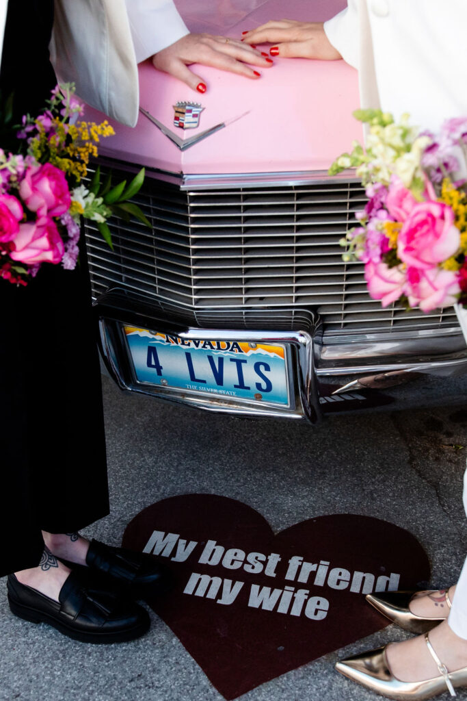 Couple posing with the Pink Cadillac at Little White Wedding Chapel